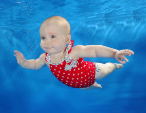 baby swimming lessons - baby in red polka dot costume swimming